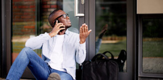 a young man on the phone telling a locksmith "I'm locked outside my house"