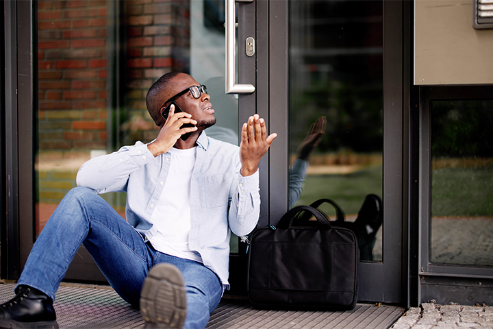 a young man on the phone telling a locksmith "I'm locked outside my house"