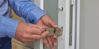A man replacing a barrel lock in a white uPVC door.