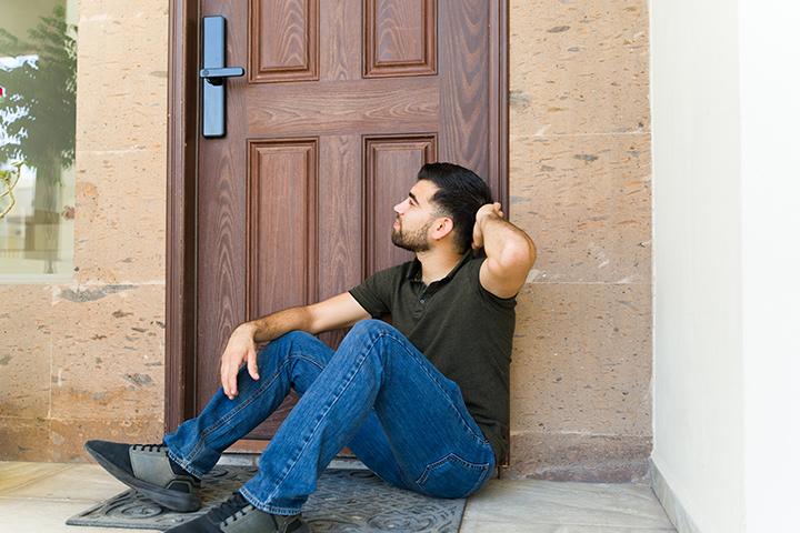 a man sitting on his door step with a hand on his head wondering how do you fix a door lock