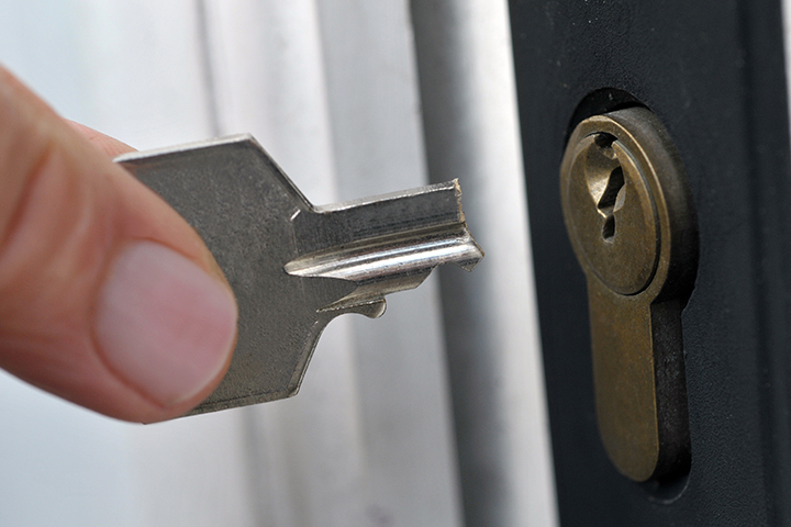 a close up of a key broken in a lock as a homeowner holds the main part wondering how to get a broken key out of a lock