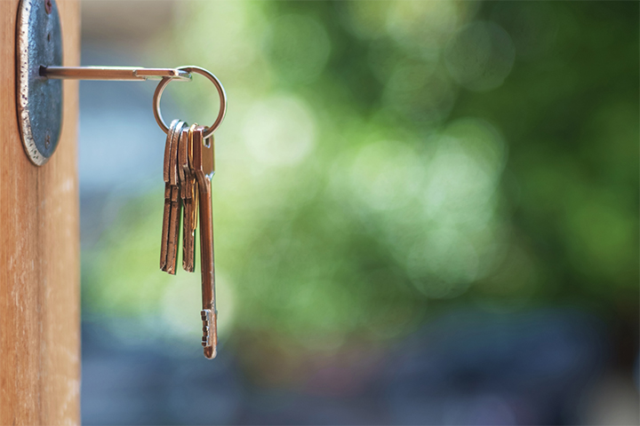 a mortice key hanging in the lock of an open front door